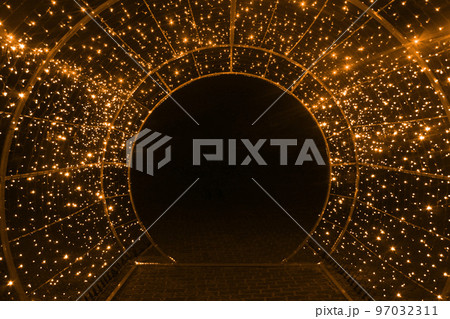 tunnel and illuminations of orange yellow white on a black dark background. New Year's Eve Christmas. Photoona festive atmosphere tunnel and illuminations of orange yellow white on a black dark background. New Year's Eve Christmas. Photoona festive atmosphere 97032311