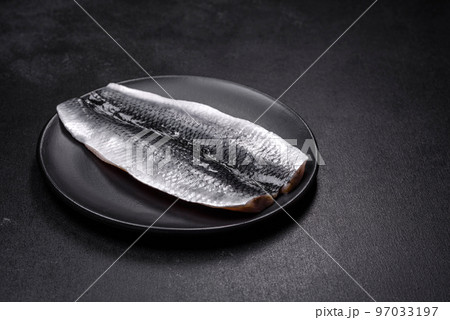 Marinated fillet with spices and herbs of sea herring on a black plate 97033197