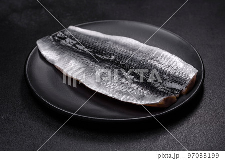 Marinated fillet with spices and herbs of sea herring on a black plate 97033199