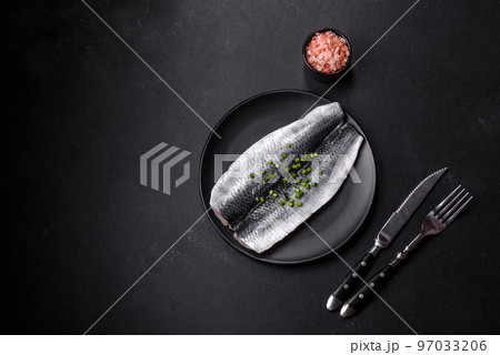 Marinated fillet with spices and herbs of sea herring on a black plate Marinated fillet with spices and herbs of sea herring on a black plate 97033206