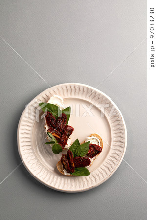 Bruschetta with sun-dried tomatoes, cream cheese and fresh vegetables. Healthy and wholesome food. Serving food in a restaurant. Photo for the menu. 97033230