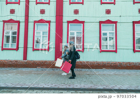 Happy female friends shopping. Two beautiful young women enjoying shopping in city with shopping bags copy space - consumerism and friendship concept 97033504
