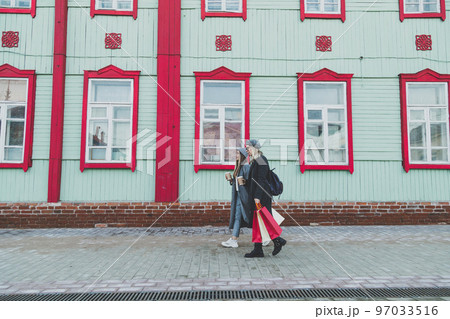 Young shopaholic friends women friends walking and carry shopping bags in the street spring or winter city with happy and smiling - purchase and free time concept 97033516