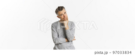 Portrait of bored and unamused middle-aged man in grey sweater, leaning on hand and looking at camera reluctant, standing sad over white background 97033834