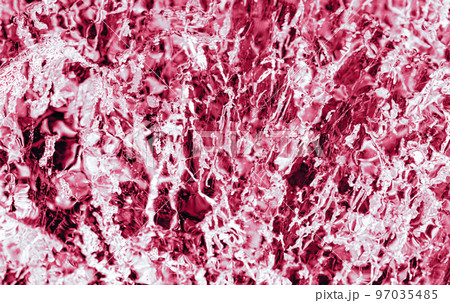 Transparent dark blue ice of frozen Baikal lake with white cracks pattern. Beautiful winter nature background. Toned image in trendy magenta color of year 2023. 97035485