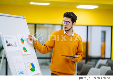 Young man leader, presenter, make a business presentation at a conference in the office. Young man leader, presenter, make a business presentation at a conference in the office. 97037078