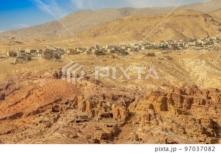 View to the ancient Nabataean Moghar Annasara tombs with Wadi Musa town in the background 97037082