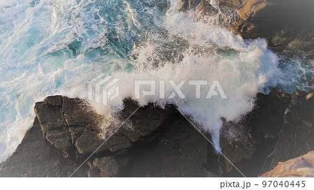 岩にぶつかり水しぶきを上げる荒波 97040445