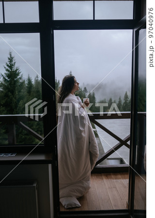 Woman drinking tea on cozy balcony of a country house. 97040976