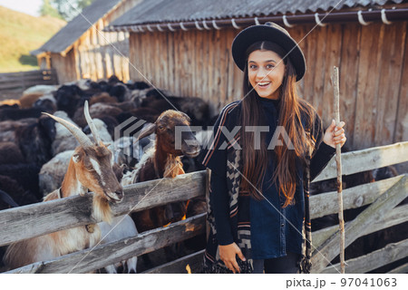 A young beautiful woman near a pen with goats A young beautiful woman near a pen with goats 97041063