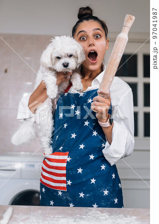 Cheerful woman with a rolling pin and white Maltese dog Cheerful woman with a rolling pin and white Maltese dog 97041987