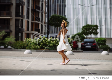 Beautiful pretty woman in white dress walking at city street Beautiful pretty woman in white dress walking at city street 97041988