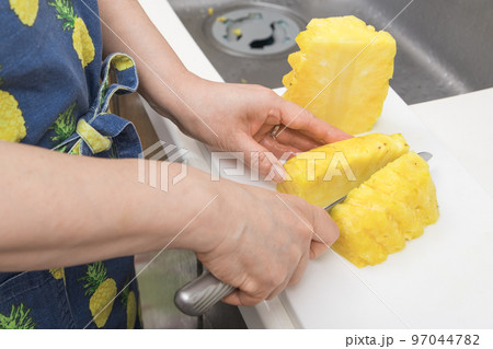 【皮削ぎの終わったパイナップルを切っていく】 97044782