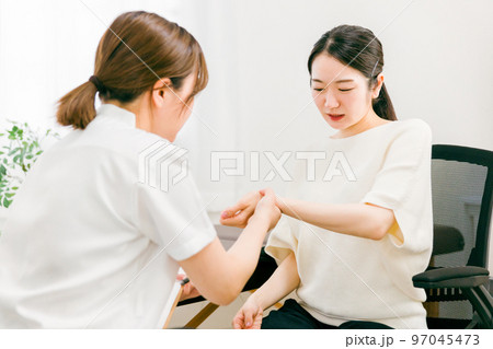 整形外科で腱鞘炎・手首の怪我をして悩む患者とカウンセリング・診察・問診する医師・看護師・カウンセラー 97045473