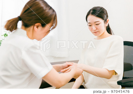 整形外科で腱鞘炎・親指の怪我をして悩む患者とカウンセリング・診察・問診する医師・看護師・カウンセラー 97045476