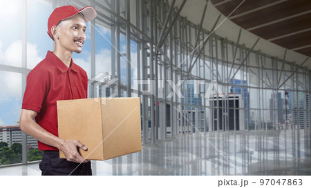 Parcel delivery man with a hat carrying a package Parcel delivery man with a hat carrying a package 97047863
