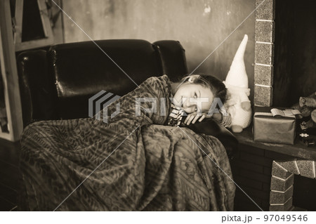 little girl sitting on cozy chair near Christmas tree in morning at home. black and white photo little girl sitting on cozy chair near Christmas tree in morning at home. black and white photo 97049546