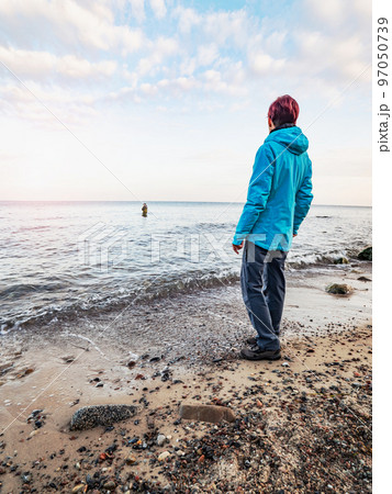 Woman is watching fishing man wading in the cold water. Man fishing 97050739