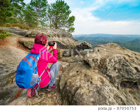 Travel hike woman sit on heels and taking photo with phone. Travel hike woman sit on heels and taking photo with phone. 97050753