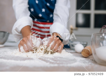 Young housewife in an apron kneads dough with her hands. 97052409
