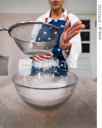 Woman sifting flour through sieve. Selective focus. Woman sifting flour through sieve. Selective focus. 97052502