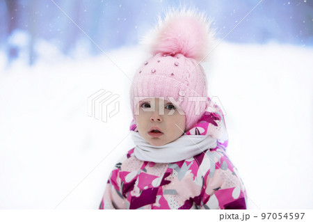 Portrait of a little girl in a winter hat on the background of winter nature. Child in winter. Portrait of a little girl in a winter hat on the background of winter nature. Child in winter. 97054597