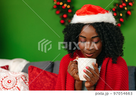 Smiling young african woman sitting on sofa in living room on Christmas Eve 97054663