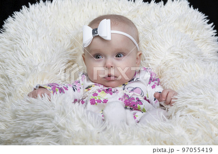 Beautiful baby in a fur blanket. The girl is four months old. Children under one year old. 97055419