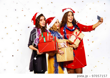portrait of three happy young women in santa claus hat with gift and sparklers .Christmas concept. 97057157