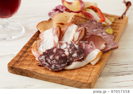 華やかなハムやサラミの盛り合わせと赤ワイン 97057358