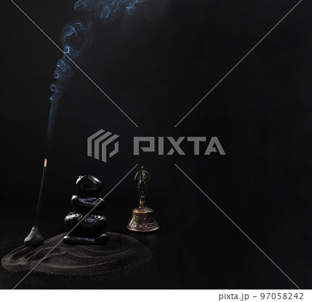 Meditation on Buddhist stones with a bell. Black stones in the sand with incense from a wooden table. Zen garden background scene. Banner, beautiful smoke. Meditation on Buddhist stones with a bell. Black stones in the sand with incense from a wooden table. Zen garden background scene. Banner, beautiful smoke. 97058242