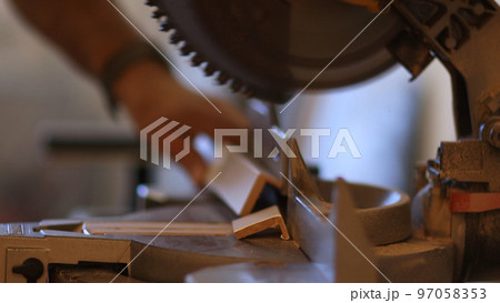 Close-up of a male master with a grinding machine for cutting cuts off a profile. Macro 97058353