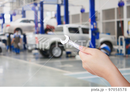 Technician holding a wrench with car repair service center background 97058578