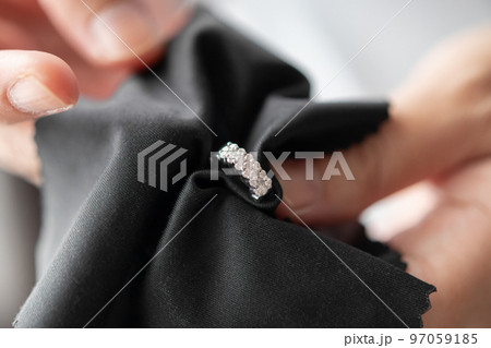 Jeweller cleaning jewelry diamond earrings with fabric cloth 97059185