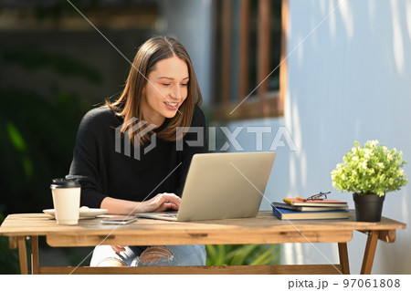 Beautiful caucasian woman having remote work on laptop computer while sitting at outdoors 97061808