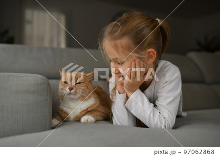 A girl near a ginger cat on the couch A girl near a ginger cat on the couch 97062868