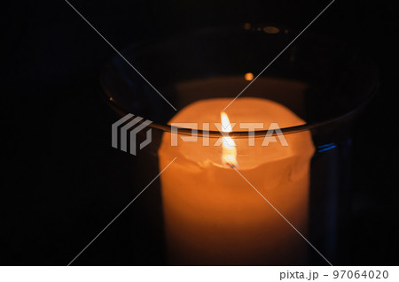 A candle in glass candlestick glows in a dark, close up photo A candle in glass candlestick glows in a dark, close up photo 97064020