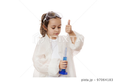 Smart primary school student, little girl in lab coat, filling the glass laboratory graduated pipette with a blue liquid chemical solution from a measuring cylinder. Kids learning chemistry. Education 97064183