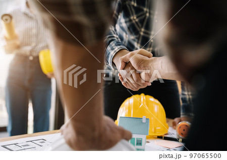 Construction workers, architects and engineers shake hands while working for teamwork and cooperation after completing an agreement in an office facility, successful cooperation concept. 97065500