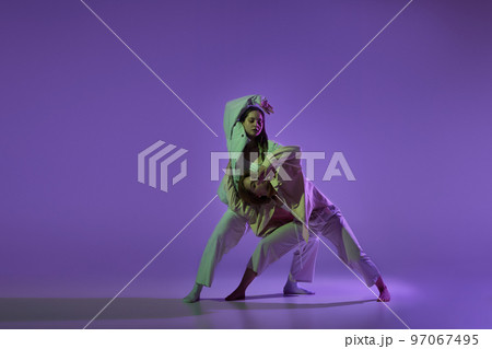 Dance performance. Stylish female dancers at contemporary choreography dance class isolated over crystal purple background. Style, youth, music and fashion Dance performance. Stylish female dancers at contemporary choreography dance class isolated over crystal purple background. Style, youth, music and fashion 97067495