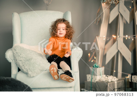 little girl sitting in a cozy chair and showing thumbs up 97068313