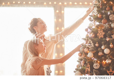happy mom and little daughter decorating the Christmas tree 97068317