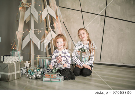 little sisters are looking at Christmas presents sitting in the modern living room 97068330