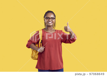 Happy african american female student in glasses showing thumb up isolated on yellow background. 97068649