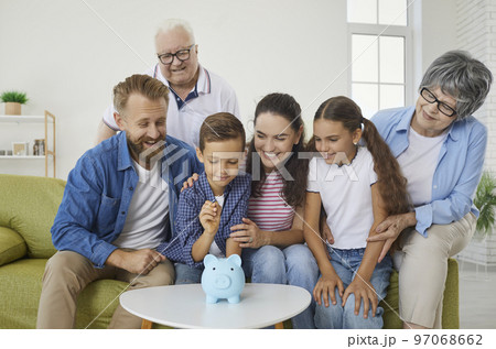 Joyful multi-generational family teaches little boy to collect money in piggy bank. Joyful multi-generational family teaches little boy to collect money in piggy bank. 97068662