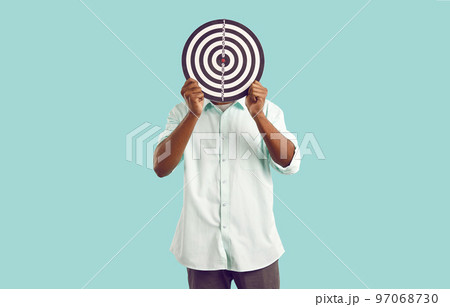 Anonymous man hides face behind dart board, symbolizing selection of target audience or targeted ads 97068730