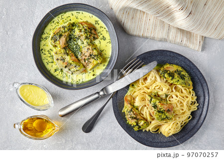 Chkmeruli, spaghetti with fried chicken, on a dark plate with cutlery, sauce, olive oil and kitchen towel Chkmeruli, spaghetti with fried chicken, on a dark plate with cutlery, sauce, olive oil and kitchen towel 97070257