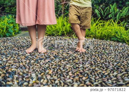 Mother and son Walking On A Textured Cobble Pavement, Reflexology. Pebble stones on the pavement for foot reflexology 97071822