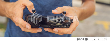 Man holds remote controller with his hands and controls the drone. New technologies and innovations concept BANNER long format Man holds remote controller with his hands and controls the drone. New technologies and innovations concept BANNER long format 97072260