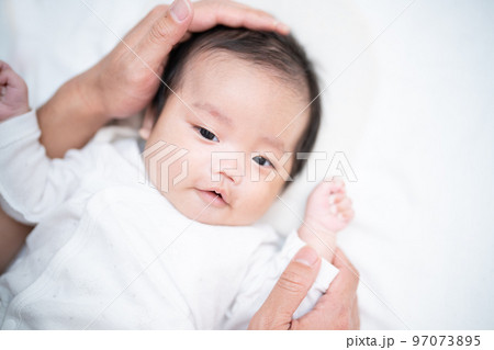 パパに手を添えられて幸せそうな生後2か月の赤ちゃん 97073895